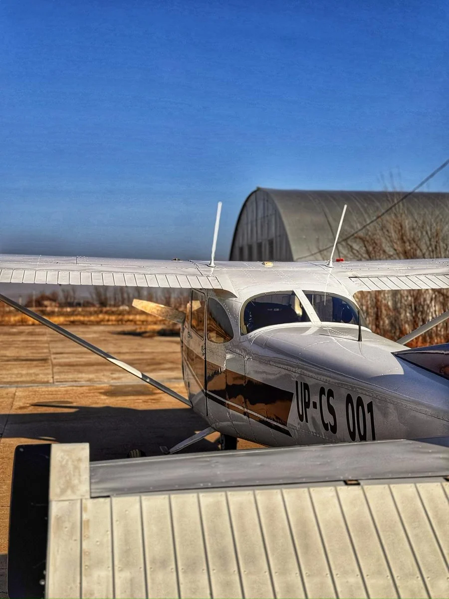 Small white aircraft parked near a hangar at an airfield outside Almaty